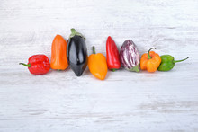 Collection Of Colorful Peppers And Eggplants Side By Side  On A White Table