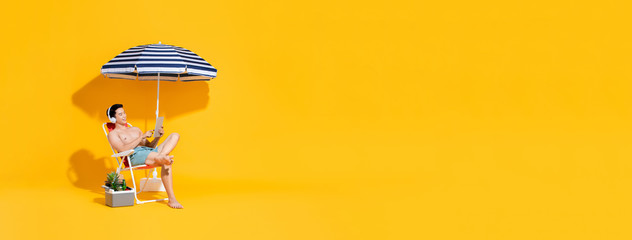 Portrait of young shirtless Asian man sitting on beach chair relaxing and listening to music in isolated summer yellow banner background with copy space