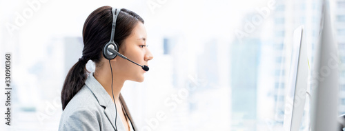 Young Asian businesswoman wearing headsets working as a customer service operator in call center city office  banner background