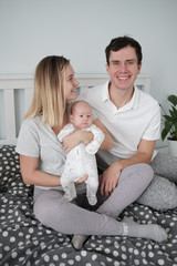 Wall Mural - Family portrait: young mom and dad with his 2 years old son and 2 month old baby