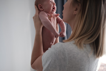 Wall Mural - Pretty woman holding a newborn baby in her arms.