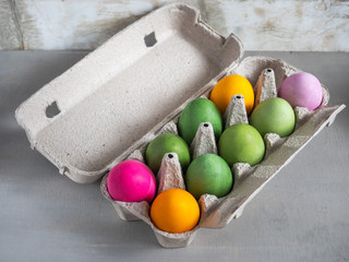 Different colored eggs on a cardboard stand on a gray table