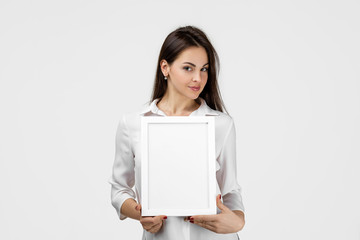 Beautiful smiling woman holding blank board for text on gray background. girl with empty frame for your text