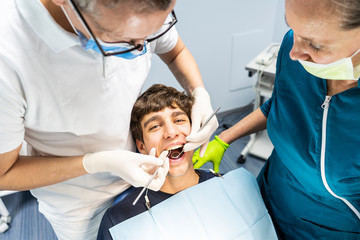 Professional dentist surgeon and assistant performing dental operation in a clinic with modern tools equipment