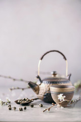 Wall Mural - Traditional asian tea ceremony arrangement. Flat lay of iron teapot, cups and blooming cherry tree flowers on grey concrete background. Spring concept. Top view. Copy space