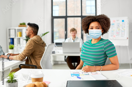 health, safety and pandemic concept - african american woman wearing protective medical mask for protection from virus at office