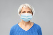 © Syda Productions - health, safety and pandemic concept - portrait of senior woman wearing protective medical mask for protection from virus over grey background