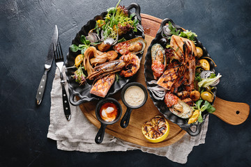 Assorted seafood on plates. Beautiful composition on a served seafood table, squid, shrimp, salmon steak and octopus. Food photo, low key, traditional Italian cuisine. Top view, save the space