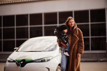 Wall Mural - Young mother with child charging electro car at the electric gas station.