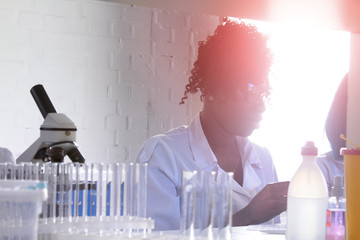 Wall Mural - Testing facility. Young African female scientist or medical student, positive young professional woman, works on testing urine, blood, nucleic acids for novel coronavirus causing covid-2019 disease.