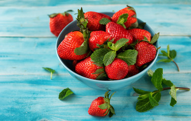 Close up of a fresh strawberry in a blue bowl on light blue background