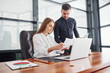 © standret - Woman and man in formal clothes working together indoors in the office by table