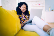 Delighted Black Teenager Browsing Social Media On Sofa