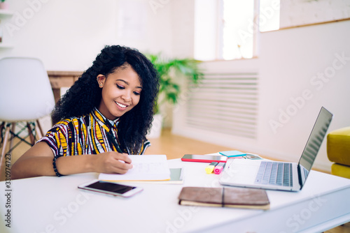 Fotografía Smiling black teenager doing homework at home