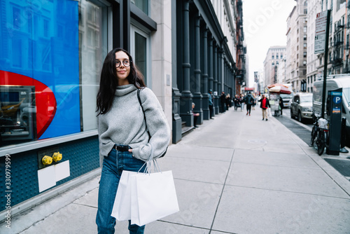 Fotografía Content woman strolling on street and carrying shopping bags