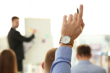 Wall Mural - Man raising hand to ask question at business training indoors, closeup