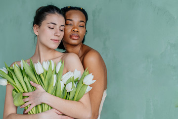 Wall Mural - Two beautiful models of African-American and European woman with clean skin and well-groomed hair isolated on white background