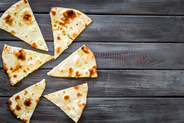 Focaccia pieces frame on dark wooden background top-down copy space