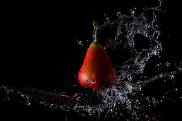 The water is splashed rose apple  on the  until the water is distributed beautifully on a black background.