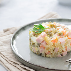 Wall Mural - Russian salad Olivier with mayonnaise served in culinary ring on plate. Light background.