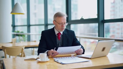 Wall Mural - Serious senior businessman in cafe. Businessman working on business project in city cafe