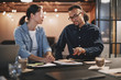 © Flamingo Images - Two young businesspeople going over paperwork together in an off