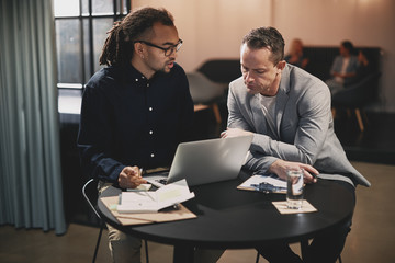 Two businessmen discussing work together at an office table