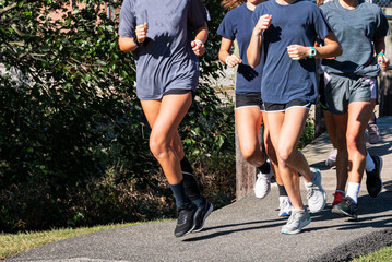 Group of girls running together on a path over a bridge