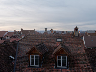 View of rooftops with beautiful roof tiles in the old medieval city of Murten or Morat in Switzerland at dusk. 