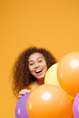 Wall Mural - Cheerful young african american girl in casual clothes isolated on yellow orange background. Birthday holiday party people emotions concept. Mock up copy space. Celebrating hold colorful air balloons.