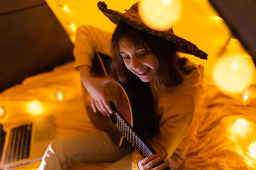 Wall Mural - little girl playing acoustic guitar under the tent in a living room.