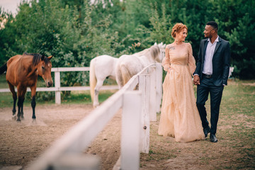 Wall Mural - Happy couple walking together on ranch with horses