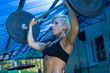 © IvSky - A young woman lifts a heavy barbell in the gym.