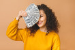 © denis_vermenko - Portrait of a cheerful young woman holding money banknotes and celebrating isolated over beige background.