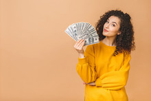 Portrait Of A Cheerful Young Woman Holding Money Banknotes And Celebrating Isolated Over Beige Background.
