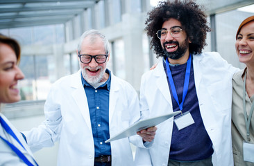 Group of doctors with tablet on conference, medical team laughing.