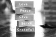 Inspirational quote - Love, peace, give, serve, grateful. With single positive word on wooden blocks in light black and white background.