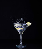 Fototapeta Łazienka - glass with martini splashes and lemon on a black background
