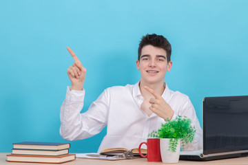 Poster - student at the desk isolated on color background at the table with books and school supplies