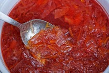 Gray Metal Spoon Picks Up Red Borsch In A White Pan