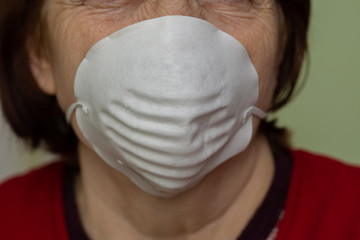 Disposable protective mask on the face of an old woman