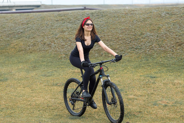 Girl on a mountain bike on offroad, beautiful portrait of a cyclist in rainy weather, Fitness girl rides a modern carbon fiber mountain bike in sportswear. Close-up portrait of a girl in red bandana.