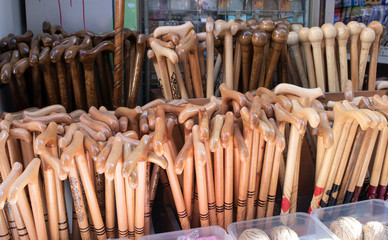 Wooden walking sticks are made for the elderly and disabled. There is more than one at the counter in front of the store. Close up.