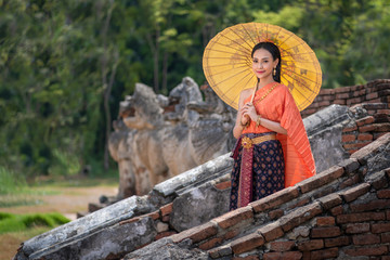 Asian women with umbrella, Pretty girl wearing in Thai traditional dress costume according Thai culture at the historical ancient temple Ayutthaya, Thailand