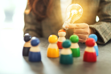 Wall Mural - closeup image of a woman holding and putting a light bulb over one of a different colors wooden peop