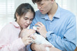 © mkitina4 - Asian family young father and mother feeding milk baby boy at home. Portrait of asian young couple father mother holding new born infant feeding nursery mother’s day concept