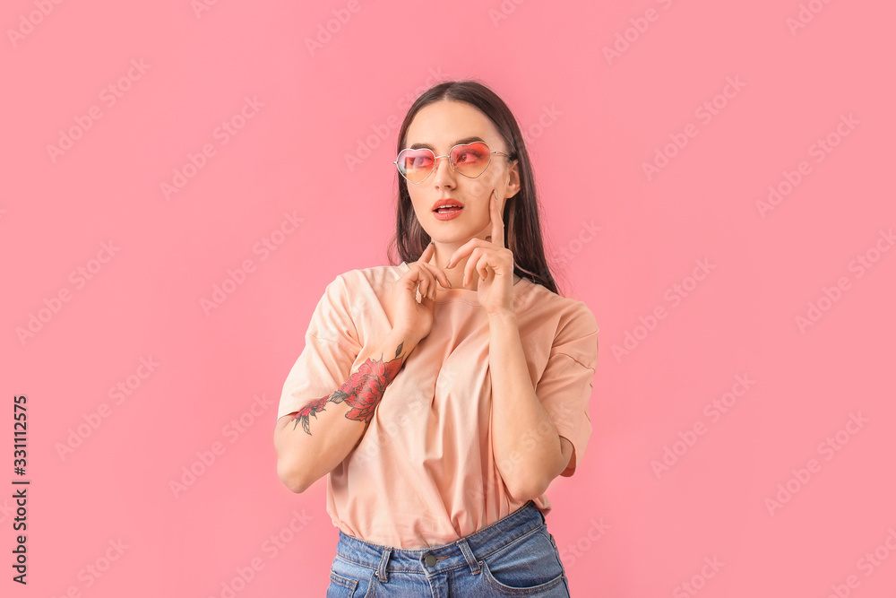 Young woman with stylish sunglasses on color background