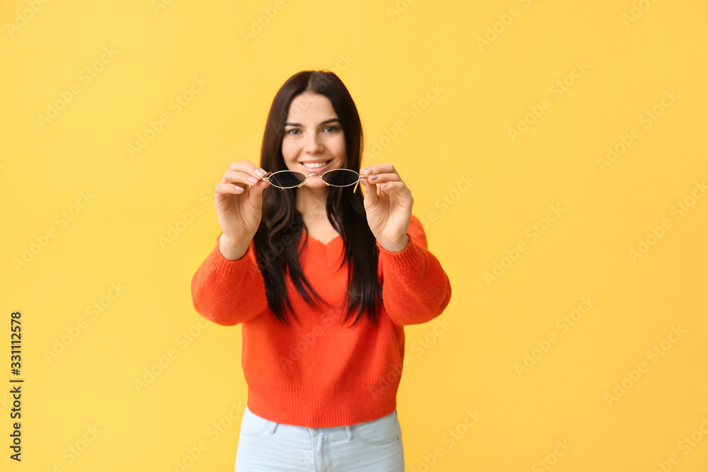 Young woman with stylish sunglasses on color background