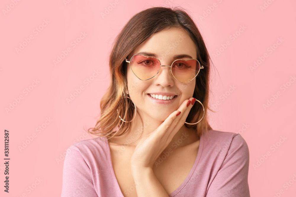 Young woman with stylish sunglasses on color background