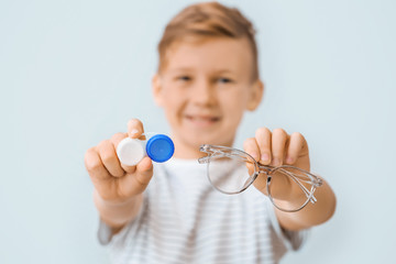 Sticker - Little boy with contact lens case and eyeglasses on grey background, closeup